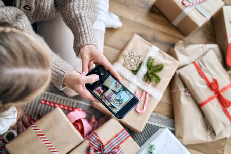 Unrecognizable woman taking picture with smart phone of wrapped Christmas presentsの写真素材