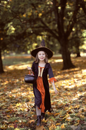 Vertical image of girl in witch outfit and walking in the woodsの写真素材