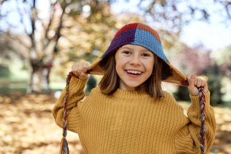 Caucasian girl standing in the woods and wearing funny colorful hat
