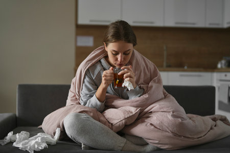 Caucasian woman covering under the duvet with tea at home