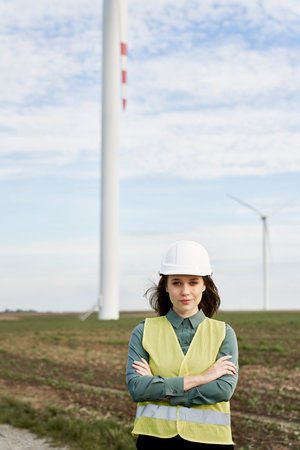 Portrait of female caucasian engineer holding digital tablet and standing on wind turbine fieldの写真素材