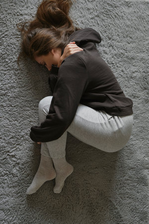 Caucasian woman lying down at the carpet in home with mental problemの写真素材