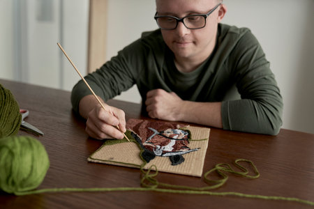 Adult caucasian man with down syndrome making a craftの写真素材