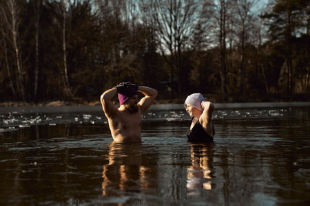 Caucasian couple standing and talking in frozen lake with hands raisedの写真素材
