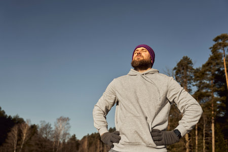 Caucasian man taking a breath and catching sunbeams outdoors in the winterの写真素材