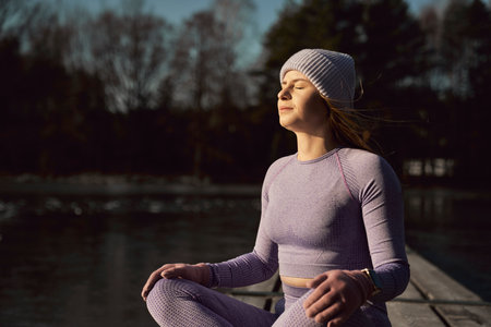 Caucasian adult woman meditating on the pier with eyes closedの写真素材
