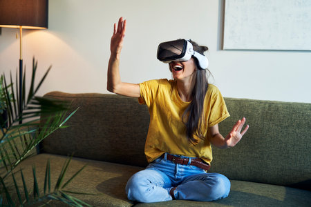 Wide shot of woman in virtual reality glasses having fun at home