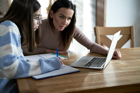 Caucasian mother with teenager daughter make homework at homeの写真素材