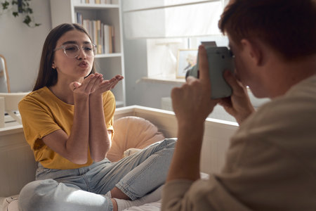 Two caucasian teenage friends taking photos in the bedroomの写真素材