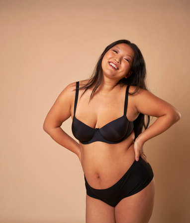 Full length of cheerful Chinese woman wearing underwear in studio shotの写真素材
