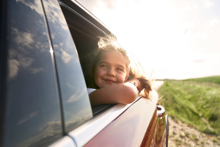 Caucasian girl of 8 years looking out of the car window while car tripの写真素材