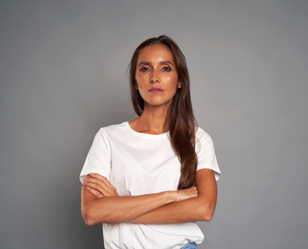 Portrait of serious caucasian woman wearing white tshirt on grey backgroundの写真素材