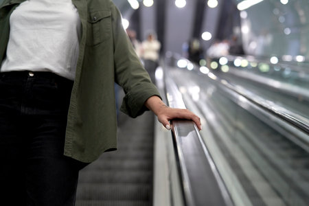 Unrecognizable woman moving on escalator in underground tubeの写真素材
