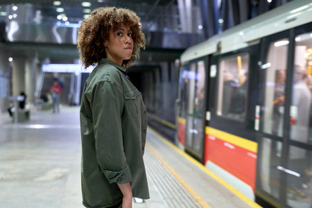 Young afro woman standing on platform and waiting for the undergroundの写真素材