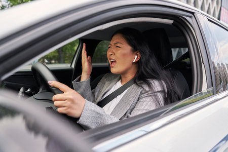 Frustrated Chinese woman screaming while driving a carの写真素材