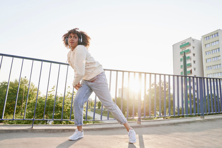 Wide shot of black woman wearing headphones and dancing on the bridgeの写真素材