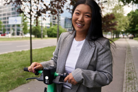 Portrait of Chinese woman standing on electric scooter in business outfitの写真素材