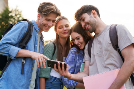 University students standing outdoors and browsing mobile phoneの写真素材