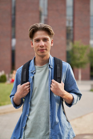 Portrait of male university student standing outside the university campusの写真素材