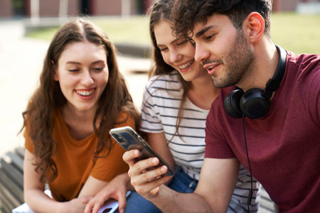 Group of students browsing phone next to to university campus