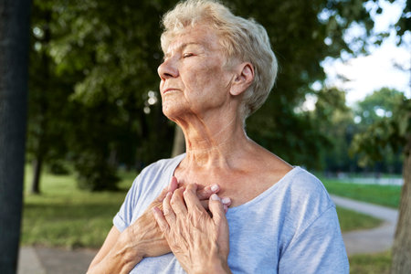 Calm senior woman doing breathing exercise in the parkの写真素材