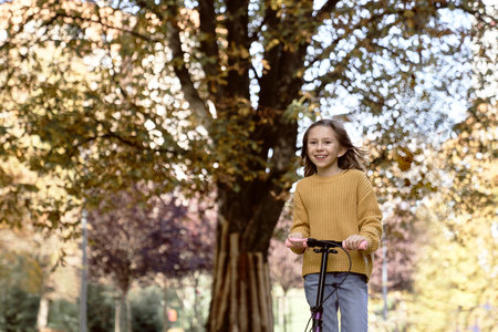 Caucasian child having fun in the woods while driving a push scooterの写真素材