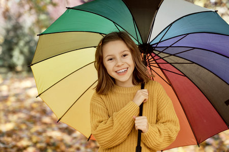 Portrait of caucasian girl in the park holding a colorful umbrellaの写真素材