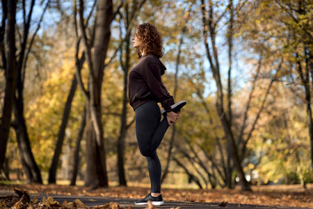 Wide shot of red head woman stretching before jogging in the parkの写真素材