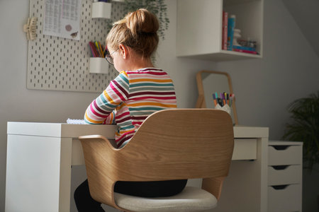 Back view of elementary age girl studying at the deskの写真素材