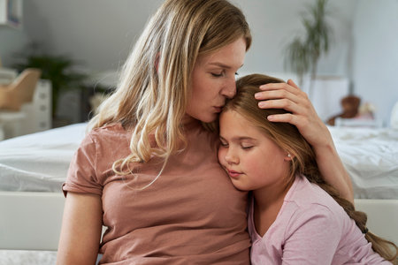 Mother giving a kiss and embracing her daughterの写真素材
