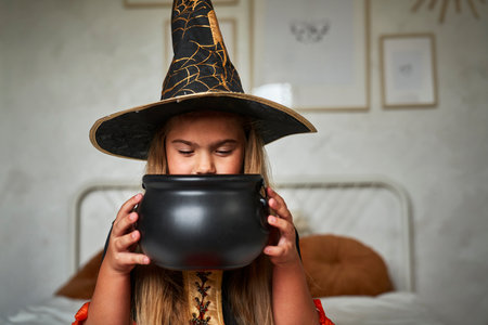 Elementary age girl wearing witch costume and looking into a jarの写真素材
