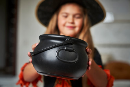Elementary age girl wearing witch costume and looking into a jarの写真素材