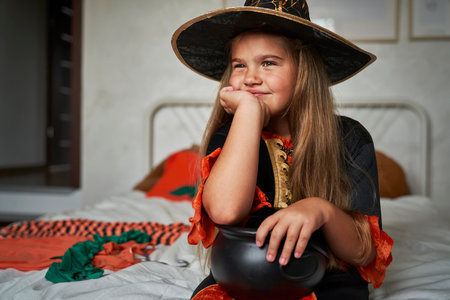 Thoughtful elementary age girl wearing witch costumeの写真素材