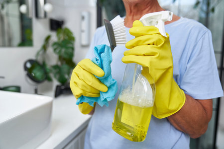 Unrecognizable woman holding cleaning products in washing up gloveの写真素材