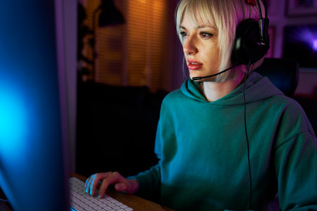 Young caucasian woman playing game at night on Desktop PC