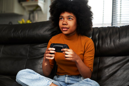 Teenage girl playing video game in the living roomの写真素材