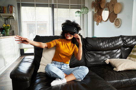 Wide shot of teenage girl wearing virtual reality simulator to play video game in the living roomの写真素材