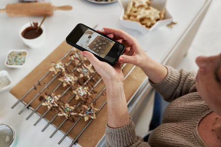 Red head woman taking picture of baked Christmas cookiesの写真素材