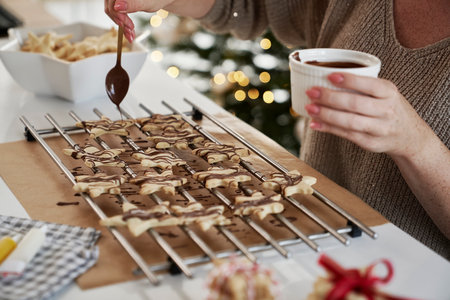 Unrecognizable woman decorating Christmas cookies with a chocolate glazeの写真素材