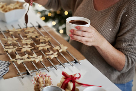 Unrecognizable woman decorating Christmas cookies with a chocolate glazeの写真素材