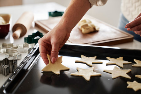 Unrecognizable woman cutting out gingerbread cookies from the doughの写真素材
