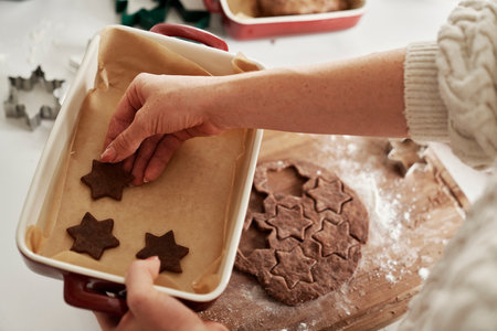 Top view of woman putting gingerbread cookies on baking trayの写真素材