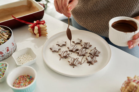 Unrecognizable woman decorating Christmas cookies with a chocolate glazeの写真素材