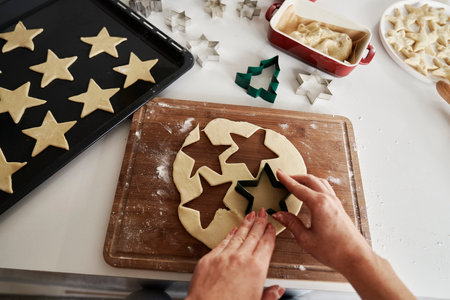 Unrecognizable woman preparing gingerbread cookies and putting them on baking trayの写真素材