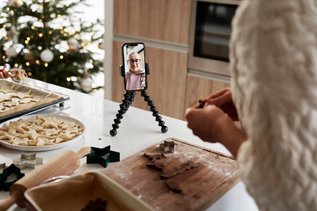 Caucasian woman preparing gingerbread cookies and having a video callの写真素材