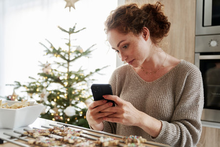 Red head woman taking picture of baked Christmas cookiesの写真素材