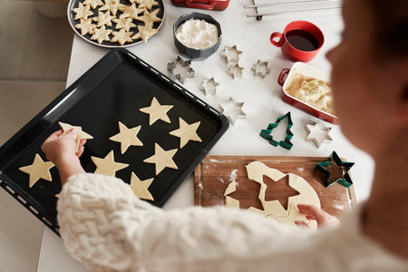 Unrecognizable woman preparing gingerbread cookies and putting them on baking trayの写真素材