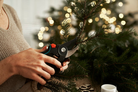 Unrecognizable woman cutting bunches for Christmas wreathの写真素材