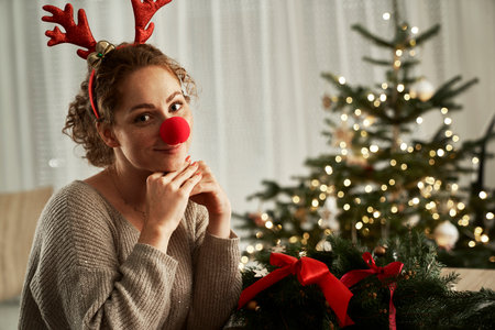 Portrait of red head woman wearing reindeer nose and headbandの写真素材