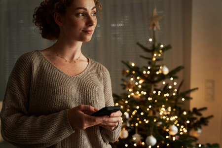 Young caucasian woman using phone at night during Christmasの写真素材